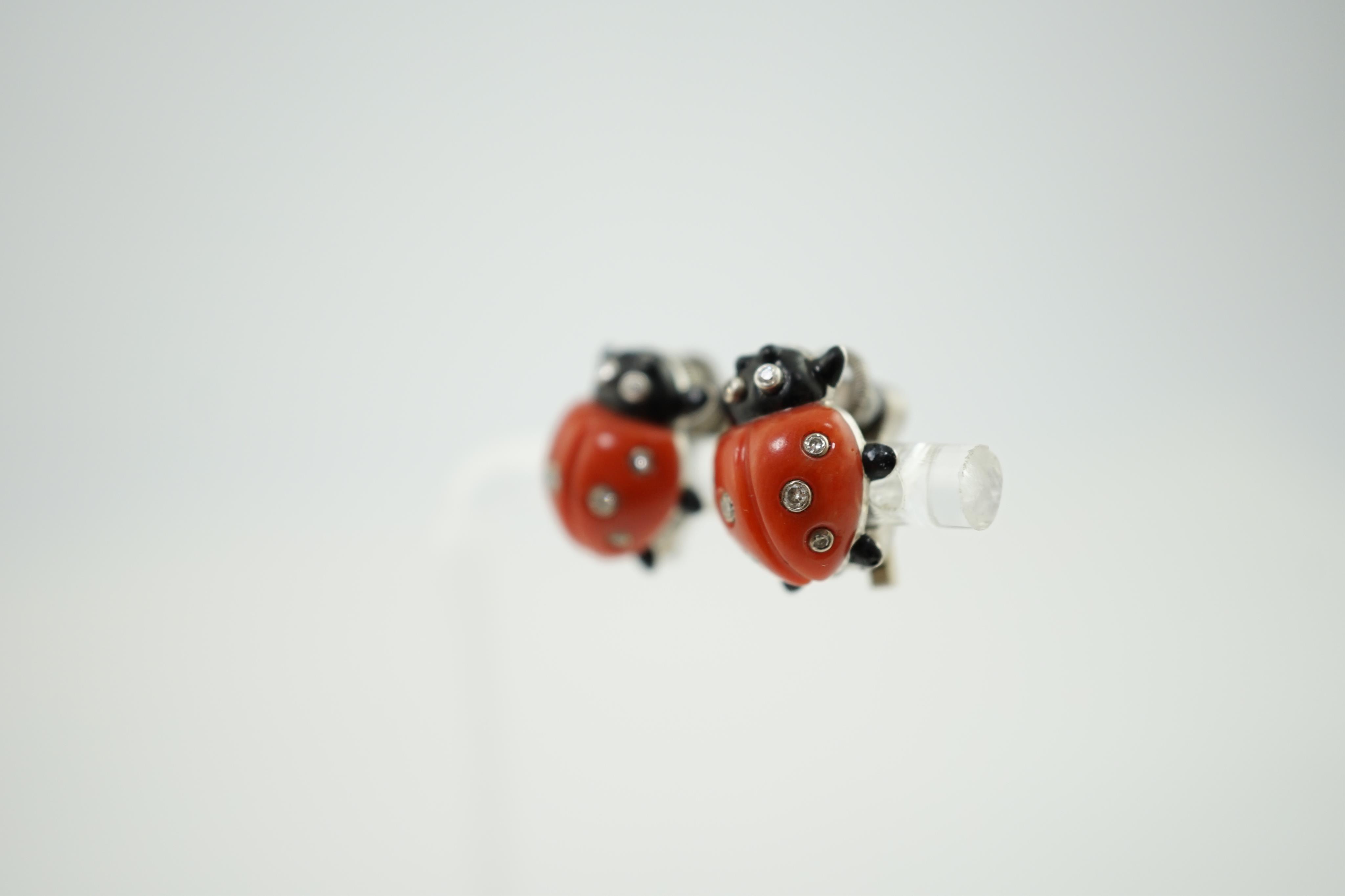 A pair of white metal, enamel, coral and diamond ladybird ear clips, bearing Cartier, New York signature and inscribed 18k